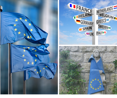 Gehisste Europaflaggen, symbolischer Wegweiser in verschiedene EU-Länder, Steinfigur gekleidet in Europaflagge